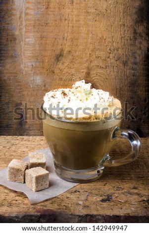 Cappuccino coffee with cream topped with sprinkled chocolate on Old grange background