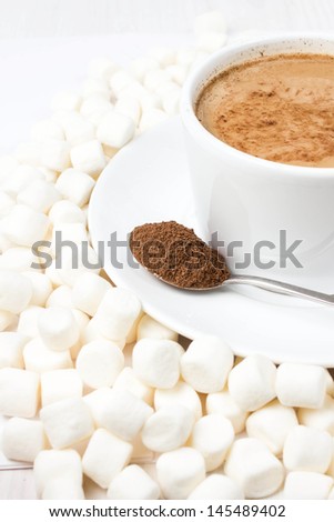 Closeup of cup of hot chocolate with small marshmallows resting on white background