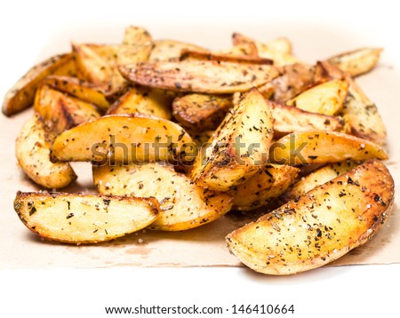 Fried french potato fries in  country styled with herbs and spices on perchament brown paper.  Fast food.  Close up.