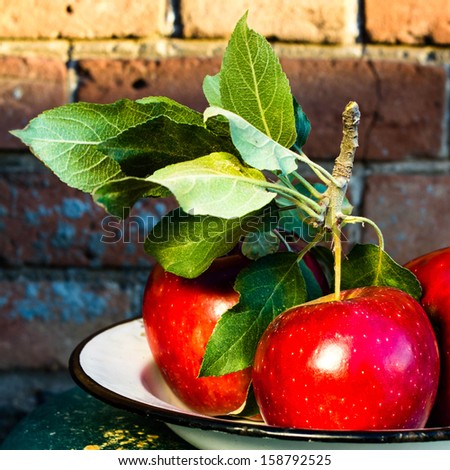 Red Big Apples with green leaves on rustic vintage background, close up. Still life photo with fresh red apple in a wooden background.