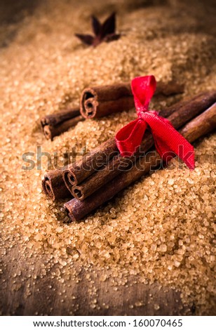 Cinnamon sticks and star anise on brown sugar on wooden background, christmas spices close up.