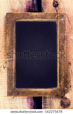 Vintage blackboard with wooden frame hanging on old wooden background. Blank black  chalk board with copy space.