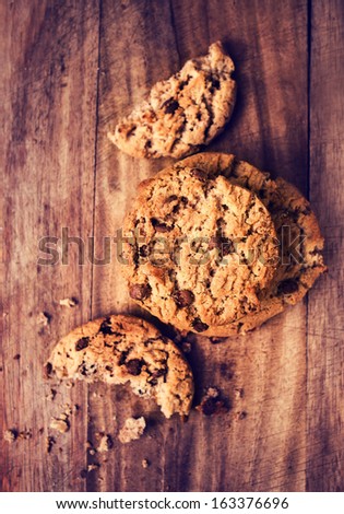 Chocolate chip cookies pile shot on wooden table, top view. Chocolate cookies over wooden background in country style.