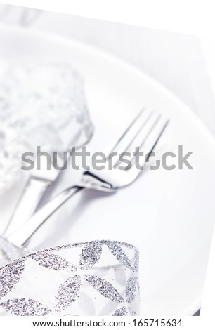 Elegant table setting place with festive decorations on white plate with silver ribbon isolated on white background,  close up.