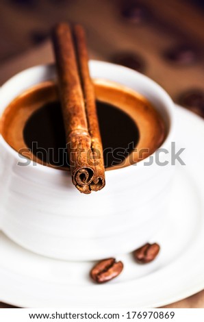Coffee cup and coffee beans with cinnamon sticks on wooden  brown background, close up. Coffee  on a wood table macro.
