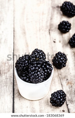Fresh Blackberries in a white bowl on  wooden background close up with copyspace in Rustic style.