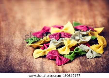 Raw Italian Pasta on wooden table with copyspace for text.  Raw Bow tie Colourful  pasta macro. Italian Food.