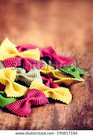 Fresh Fresh Italian Pasta on old vintage wooden table. Raw Bow tie colourful  pasta close up.