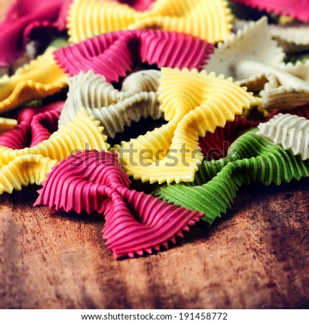 Raw Bow tie pasta  with variety of flavours - beetroot, herb, spinach isolated on old vintage wooden