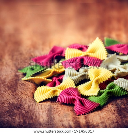 Italian Food - Fresh Italian Pasta on dark wooden table close up.  Raw Bow tie Colourful  pasta macro.