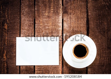 Black  Coffee cup and blank business card on wooden table. White Card for text and Coffee, top view.