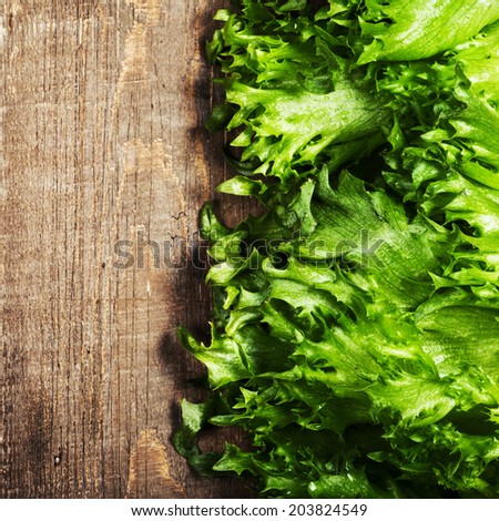 Fresh green salad over wooden background - healthy or vegetarian food concept. Lettuce Salad background with copyspace.