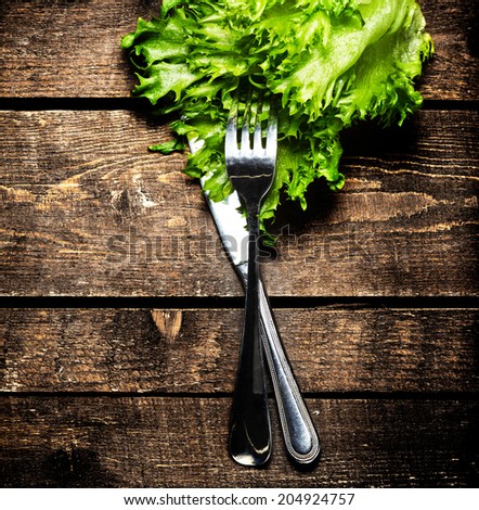 Fresh Salad over wooden table with knife and fork.  Diet Food and healthy lifestyle concept macro.
