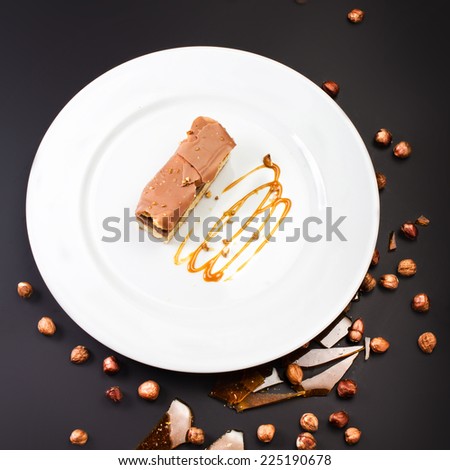Chocolate Layer Cake with caramel, nuts and chocolate on white plate, studio shot, close up. Italian sweet dessert concept.