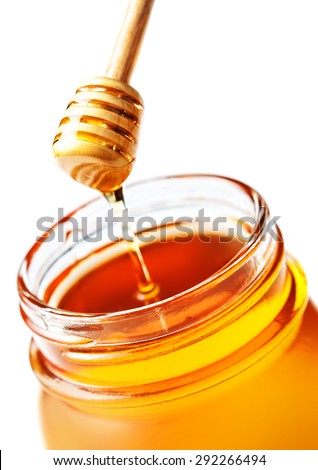 Honey Dipping with honey in glass jar isolated on white background macro. Wooden honey dipper close up.