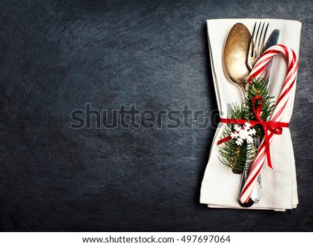 Christmas table setting with festive decorations on white tablecloth over black  background with copy space.