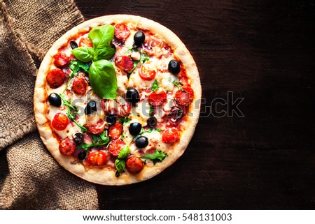 Hot pizza with Pepperoni Sausage on a dark background, top view.  Pizza on the black table with copy space.