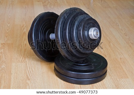 A free weight dumbbell sitting on a wood floor