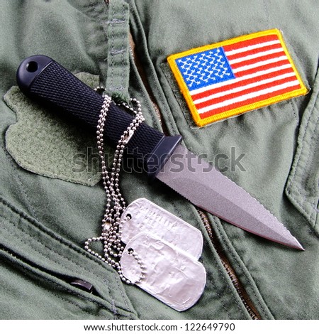 Military dog tags, boot knife and American Flag patch on pilot flight suit