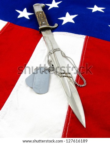 Vintage bayonet and military dog tags on vivid stars and stripes background