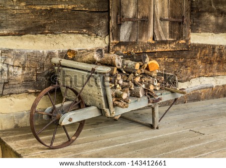 Rustic wheel barrow carrying fire wood on a log cabin porch