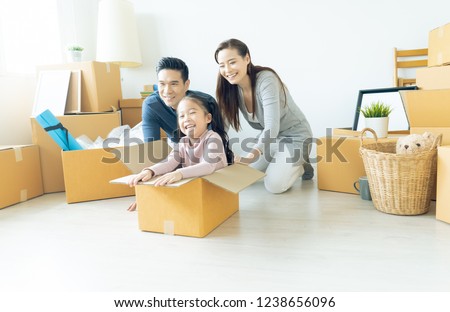 Happy young Asian family of three having fun moving with cardboard boxes in new house at moving day. Moving house day and express delivery concept.