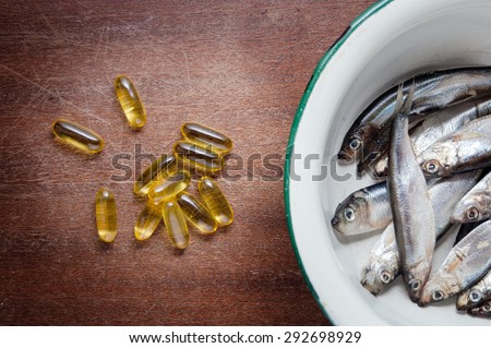 fish in white enamel bowl iron and vitamins omega three on a brown wooden table