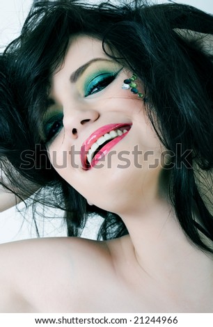 Portrait of smiling woman with colorful makeup and messy hair