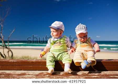 Two five months old brother twins sitting on a beach jetty