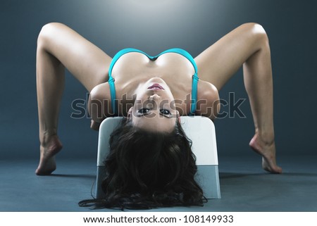 Young gorgeous woman gymnast excercising on bench