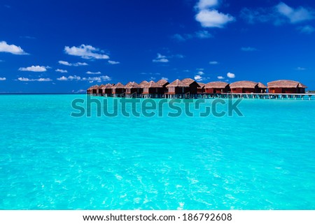 Overwater villas in blue tropical lagoon of shallow water