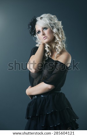 Young blonde woman in black lace see-through dress in studio