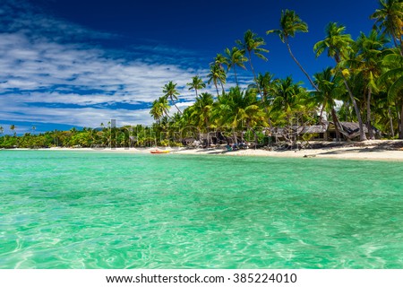 Tall coconut palm trees over tropical island resort beach in Fiji
