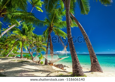 Empty hammock in the shade of palm trees on vibrant tropical Fiji Islands
