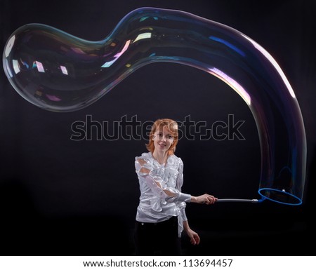 girl is doing soap bubble show on the black background