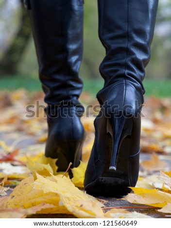 Young woman in black boots on heels in the autumn