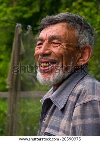 A portrait of the old weather-burned smiling man with grey beard.