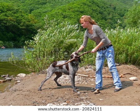 A girl plays with dog at river.
