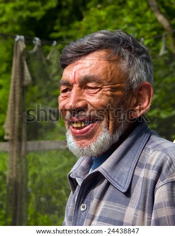 A portrait of the old weather-burned smiling man with grey beard.