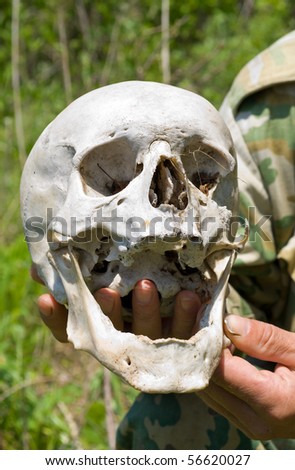 A close up of the human skull in hand of ranger. The skull of the unknown person has been found in a wood. Investigation is made.