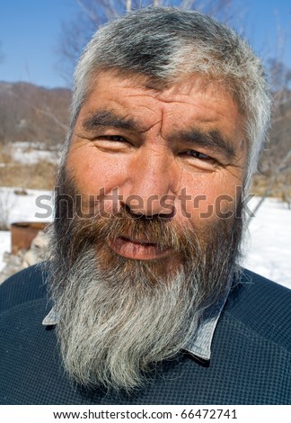 A portrait close up of the old mongoloid man with grey beard.