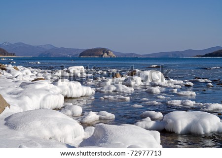 The small island in sea. Winter, stones and ice.