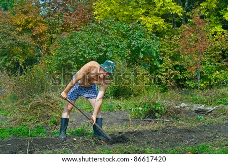 A man on garden digs the ground with spade.