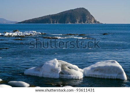 The small island in winter sea, stones and ice.