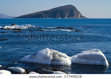 The small island in winter sea, stones and ice.