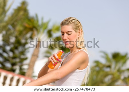 pretty girl in a wet shirt is applying sun blocker spray