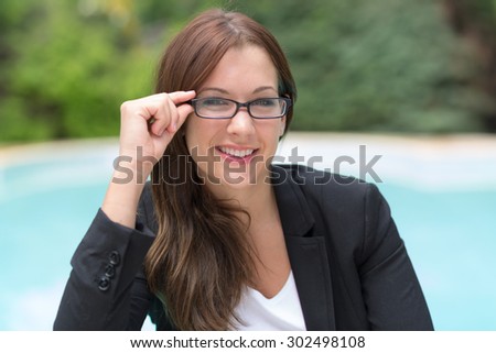 young pretty woman with glasses in business attire in front of a swimming pool