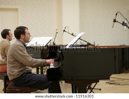 A pair of twin professional piano players performing in a recording hall