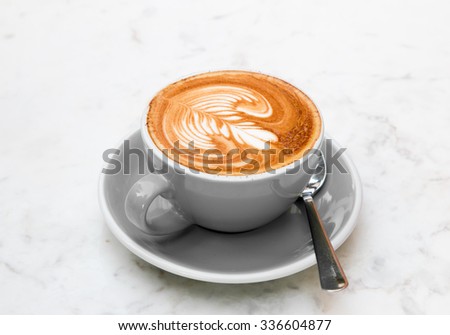 Cup of coffee green style vintage and fragrant coffee with heart flower shape in marble background . Focus on coffee foam on the top left edge of glass.