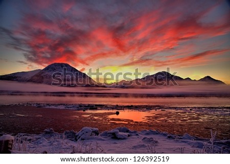 Sunset over Cook Inlet as ice fog rises above the water.